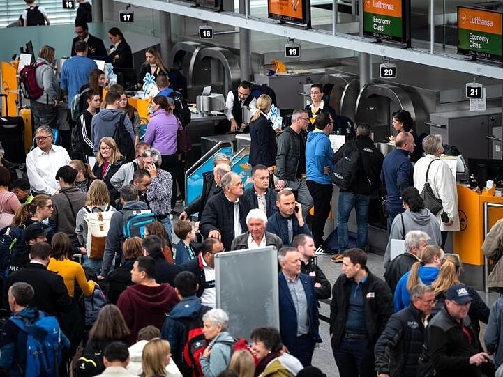 Reisende laufen durch den Flughafen München. Foto: Sina Schuldt/dpa