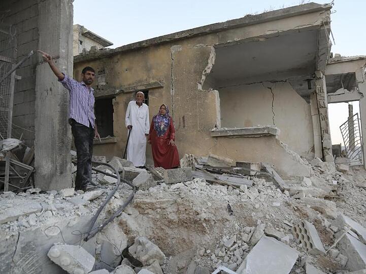 Bürger begutachten den Schaden an einem Haus, das bei Luftangriffen auf den Ort Muhambai zerstört wurde. Bei den Angriffen auf Syriens letztes großes Rebellengebiet um die Stadt Idlib sind Aktivisten zufolge 13 Menschen getötet worden.