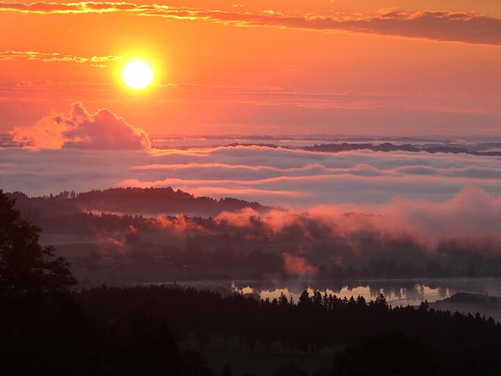 Morgennebel lichtet sich bei Sonnenaufgang über einem See. Foto: Karl-Josef Hildenbrand/dpa/Symbolbild