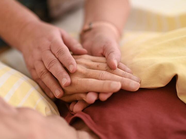 Eine Hospizmitarbeiterin hält die Hand eines todkranken Menschen. Foto: Felix Kästle/dpa/Symbolbild