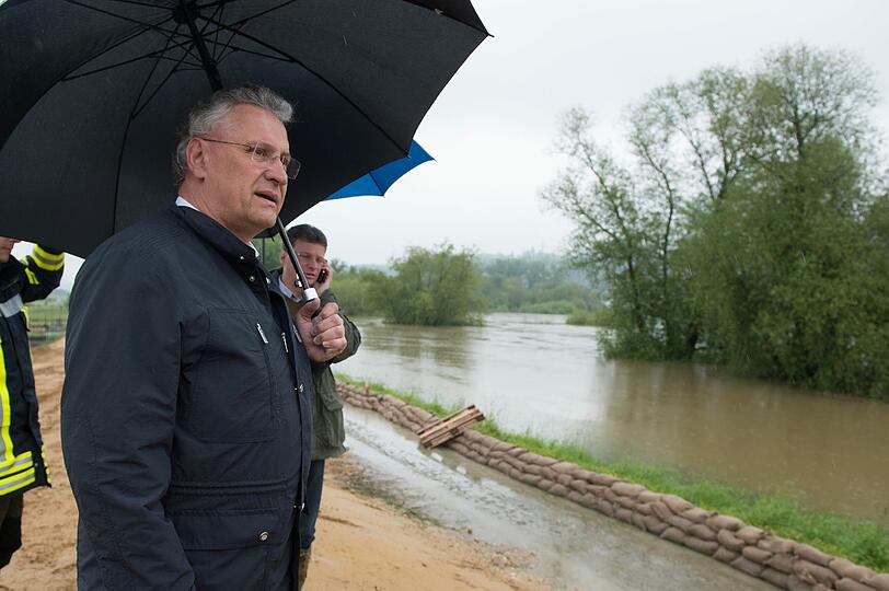 Innenminister Herrmann blickt auf die überflutete Landschaft.