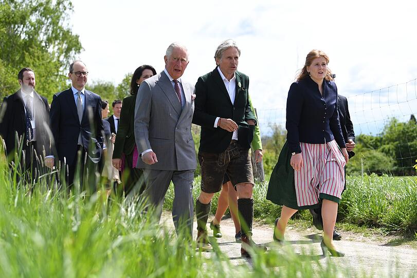 Charles geht mit Georg Schweisfurth (2.v.r) und Sophie Schweisfurth (re.) über das Hofgelände.