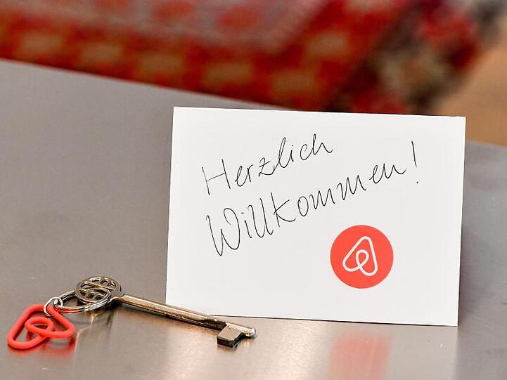 Ein Schlüssel mit einem Airbnb-Anhäger und eine Herzlich-Willkommen-Karte in einer Ferienwohnung. Foto: Jens Kalaene/zb/dpa/Symbolbild