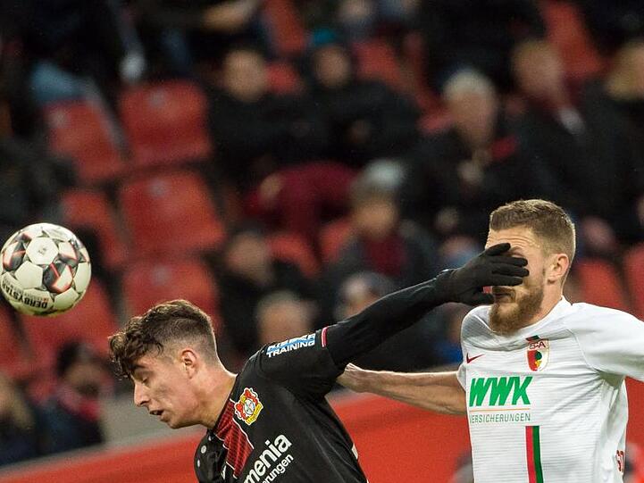 Leverkusens Kai Havertz und Augsburgs Jeffrey Gouweleeuw (l-r.) kämpfen um den Ball. Foto: Rolf Vennenbernd