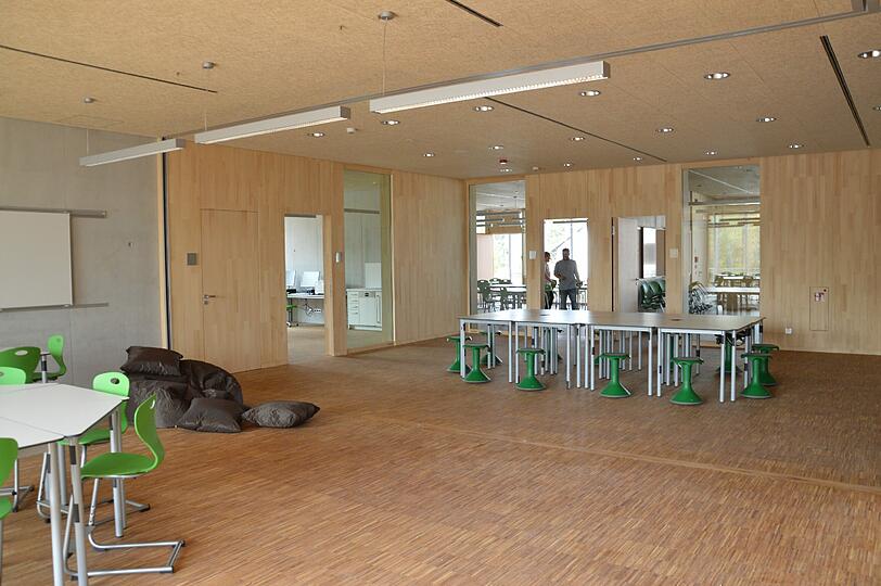 Im Gruppenraum steht ein langer Tisch mit grünen &bdquo;Hockis&ldquo;, auf denen die Kinder im Sitzen schaukeln können. Von dort führen Türen zu den Klassen- und Lehrerzimmern. Der Clou: Die hölzernen Wände lassen sich wegschieben &ndash; so entstehen flexibel große Räume.
