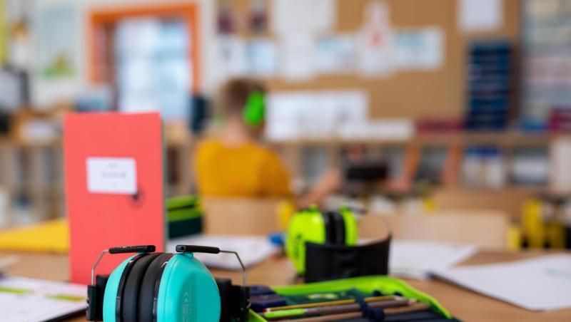 Ein Mäppchen und ein Gehörschutz liegen im Klassenzimmer einer Grundschule auf einem Tisch. Ein Mäppchen und ein Gehörschutz liegen im Klassenzimmer einer Grundschule auf einem Tisch.