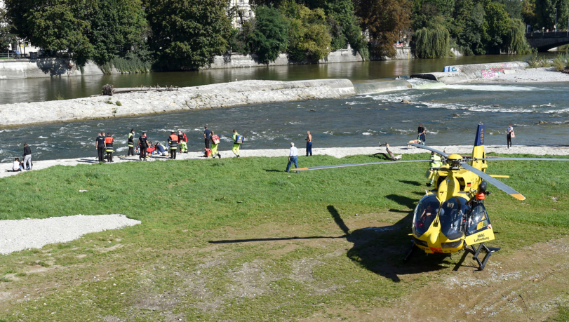 Einsatzkräfte von Feuerwehr und Notarzt an der Isar in der Nähe der Reichenbachbrücke. Auch ein Helikopter landete am Unfallort.