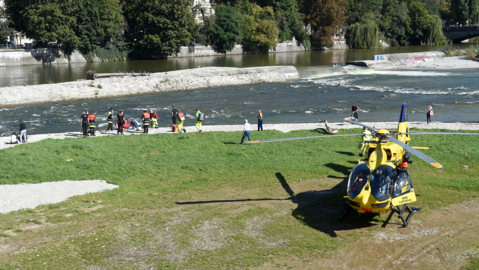 Einsatzkräfte von Feuerwehr und Notarzt an der Isar in der Nähe der Reichenbachbrücke. Auch ein Helikopter landete am Unfallort.