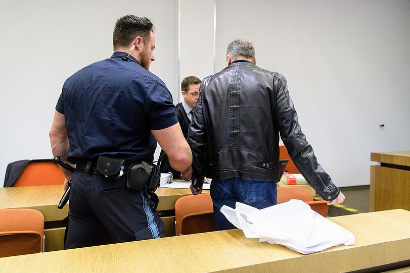 Der wegen millionenschweren Betrugs und Hochstaplerei angeklagter Mann (r.) wird zu Beginn von seinem Prozess von einem Gerichtspolizisten in einen Gerichtssaal vom Landgericht geführt.