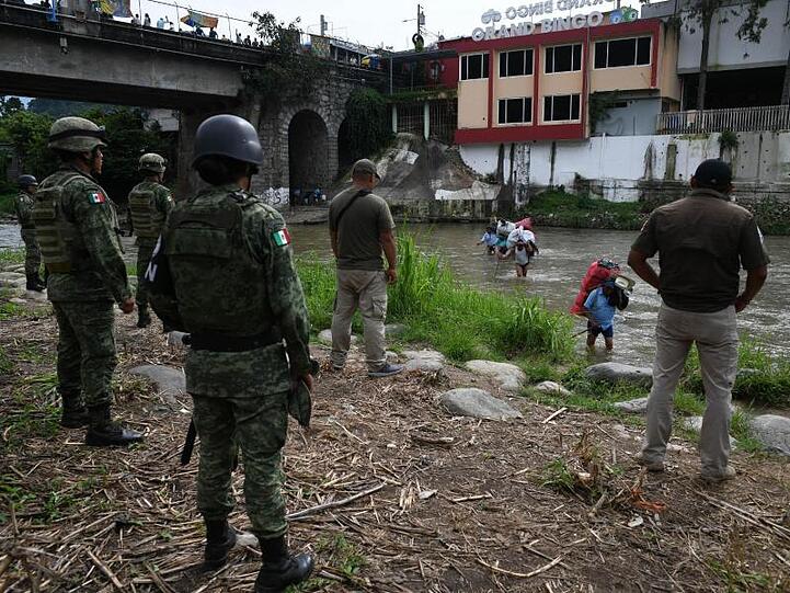 Mexikanische Soldaten und Einwanderungsbeamte beobachten Migranten aus Guatemala beim Versuch, durch einen Fluss illegal einzuwandern.