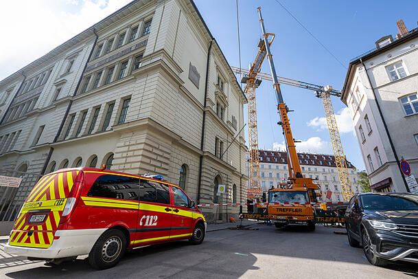 Ein Einsatzleitwagen der Feuerwehr steht an der Zufahrt zu der Baustelle in der Innenstadt, auf der ein Kran umzustürzen droht.
