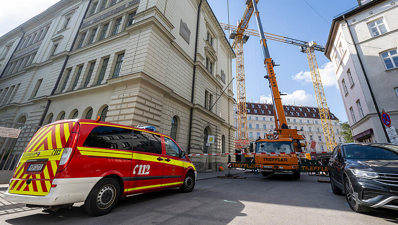 Ein Einsatzleitwagen der Feuerwehr steht an der Zufahrt zu der Baustelle in der Innenstadt, auf der ein Kran umzustürzen droht.