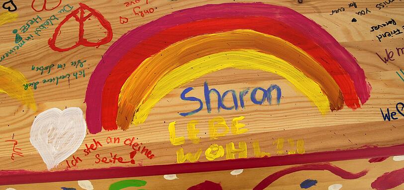 "Sharon, lebe wohl", hat ein Kind unter einen gemalten Regenbogen geschrieben. Daneben steht: "Ich steh an deiner Seite".
