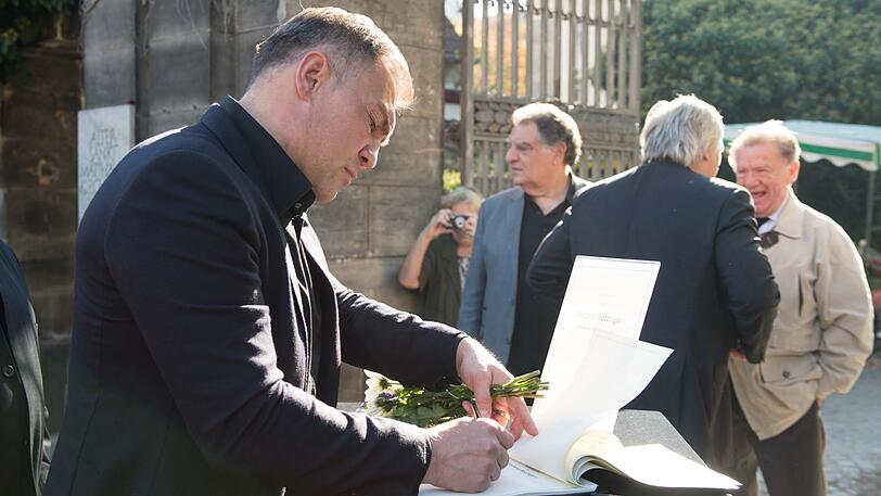 Der ehemalige Boxer Dariusz Michalczewski trägt sich in eine Kondolenzliste am Eingangstor zum Friedhof ein.