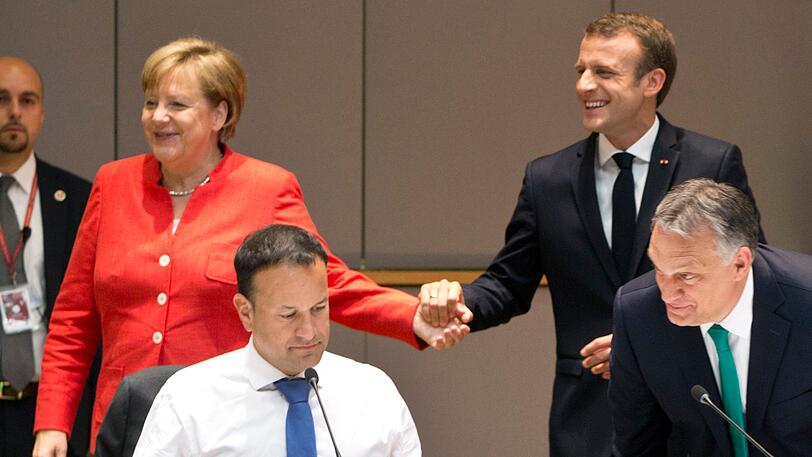 Brüssel: Bundeskanzlerin Angela Merkel (CDU) hält die Hand von Emmanuel Macron (r), Präsident von Frankreich, bei einem Frühstückstreffen am zweiten Tag des EU-Gipfels.