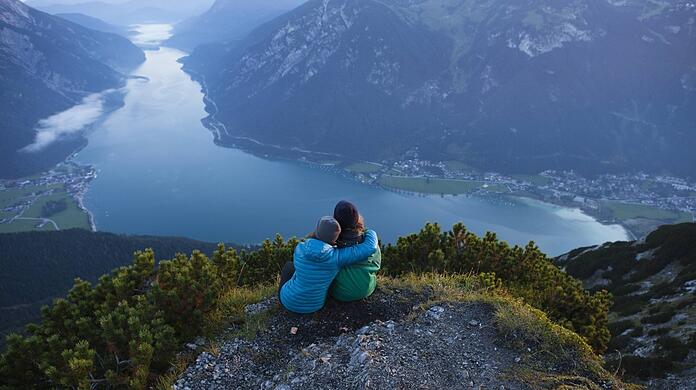 Zwei Wanderer bewundern den Achensee in Tirol - und wer nicht zu lange bleibt, kann es ihnen trotz Einreisebeschränkung gleichtun.