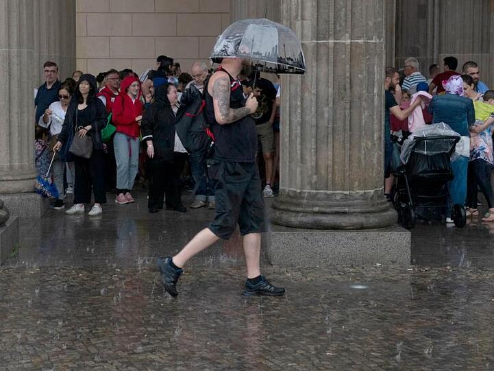 Touristen suchten am Pariser Platz in Berlin vor dem Regen Schutz.