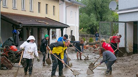 Helfer schaufen in Simbach die Schlammmassen weg.