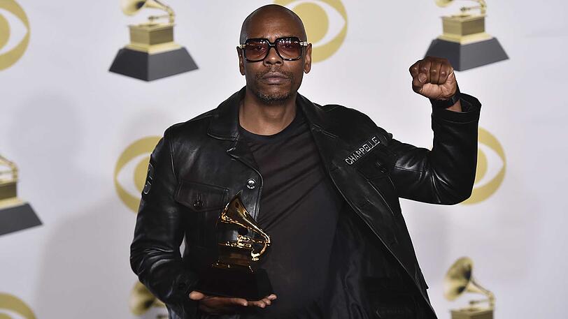 Dave Chappelle zeigt seine Auszeichung.
