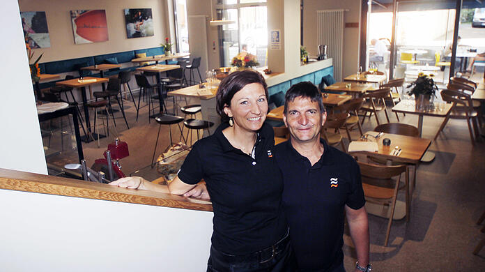 Hohe Tische im Eingangsbereich, kleine Tische aus hellem Holz daneben, an den Wänden Fotos von der Eisbachwelle. Stefanie und Gerhard Oberberger haben ihr Lokal komplett selbst eingerichtet.