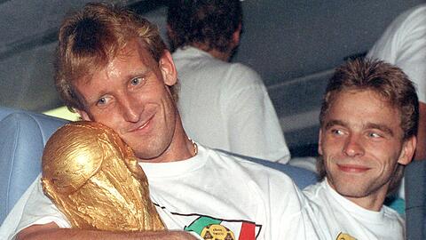 Andreas Brehme (l) mit dem WM-Pokal nach dem Finalsieg 1990 gegen Argentinien. Rechts daneben sein Mitspieler Thomas Häßler.