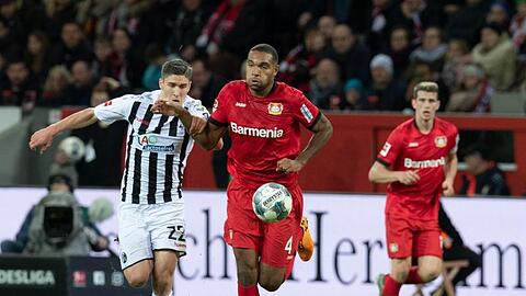 Leverkusens Jonathan Tah (M) und Freiburgs Roland Sallai kämpfen um den Ball.