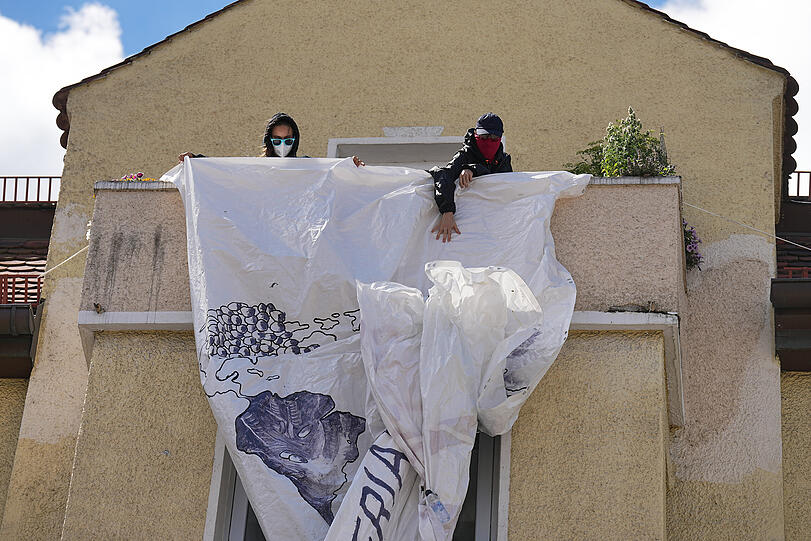 Demonstranten entrollen ein Anti-G7-Banner von einem Balkon.