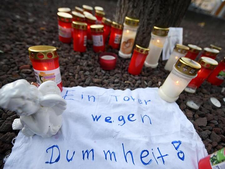 Am Königsplatz liegt eine Engelsfigur auf einem Stück Stoff, auf dem steht "Ein Toter wegen Dummheit". Foto: Stefan Puchner/dpa