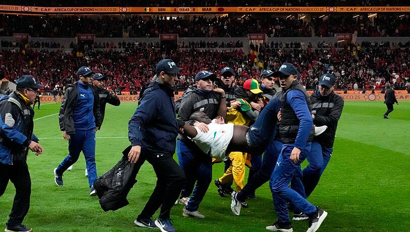 Ein auf den Platz gest&uuml;rmter Anh&auml;nger des Senegals wurde von Sicherheitskr&auml;ften weggetragen. (Archivbild)