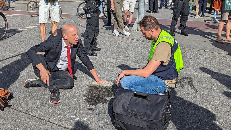 Ein Klimaaktivist hat sich mit Zement an einer Fahrbahn auf dem Münchner Karlsplatz (Stachus) fixiert. Die Polizei war dort am Freitag wegen einer Blockadeaktion der Gruppe Letzte Generation im Einsatz.
