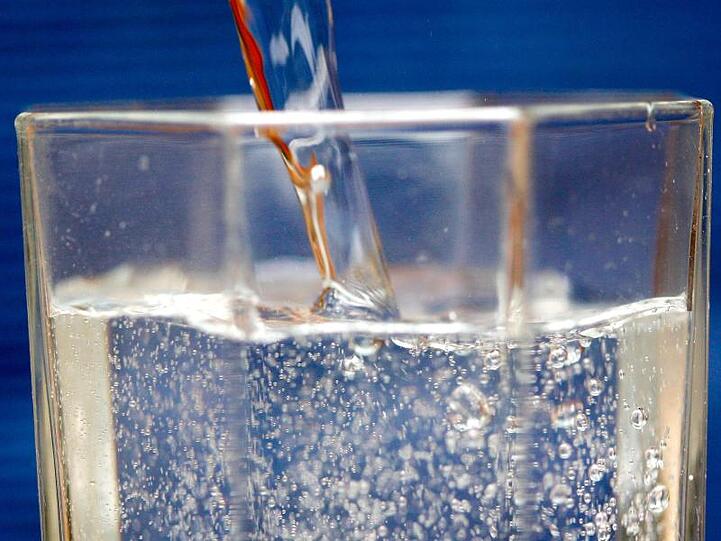 Mineralwasser wird in ein Wasserglas gegossen.