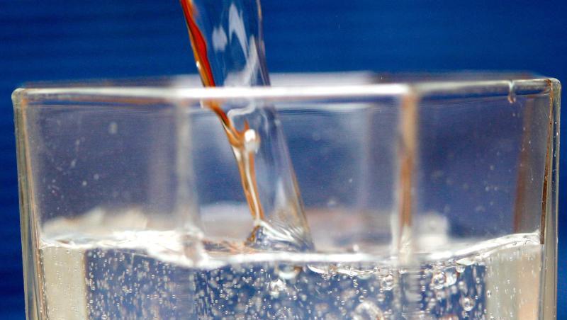 Mineralwasser wird in ein Wasserglas gegossen. Mineralwasser wird in ein Wasserglas gegossen.