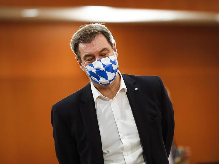 Markus Söder, Ministerpräsident von Bayern, trägt eine Gesichtsmaske mit dem weiß-blauen Rautenmuster Bayerns. Foto: Markus Schreiber/AP-Pool/dpa
