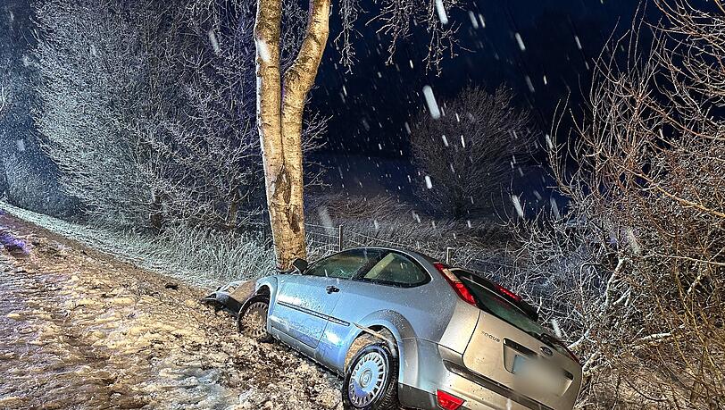 Ein Auto landet bei schneeglatter Fahrbahn an einem Baum.