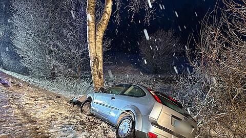 Ein Auto landet bei schneeglatter Fahrbahn an einem Baum.
