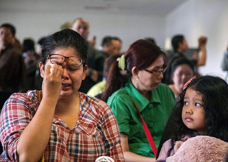 Banges Warten auf Neuigkeiten zu Flug QZ8501: Verwandte der Passagiere brechen am Flughafen in Surabaya in Tränen aus.