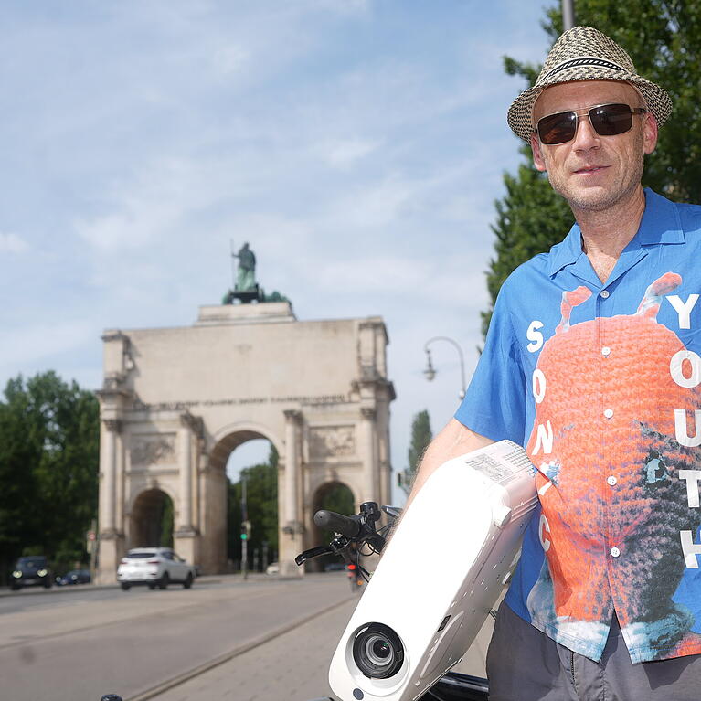 Michael Aichner aka "genelabo". Der Projektionsk&uuml;nstler ist einer der M&uuml;nchner Pioniere in seinem Beruf. Im Arm h&auml;lt er einen modernen Videoprojektor: Panasonic VZ570. Ihn montiert er meist auf das Projektions-Lastenradl.