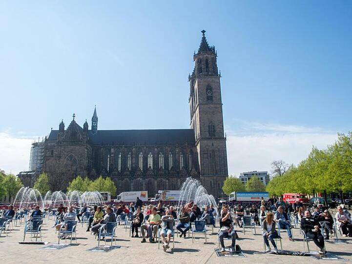 Teilnehmer lassen sich in Magdeburg nach dem Ende der Aktion vor dem Dom auf den Stühlen nieder.
