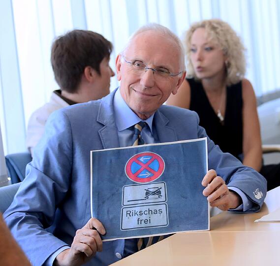 Wilfried Blume-Beyerle bewahrt Haltung, obwohl seine Pressekonferenz so gar nicht planmäßig abläuft. Trotzig lächelnd hält er für die Fotografin das geplante und umstrittene Rikscha-Haltestellen-Schild hoch. Ob ihn in den kommenden Wochen ein Rikscha-Fahrer mitnimmt?
