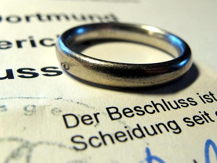 Ein Ehering lieg auf einem Gerichtsbeschluss über eine Scheidung. Foto: Franz-Peter Tschauner/dpa/Symbolbild