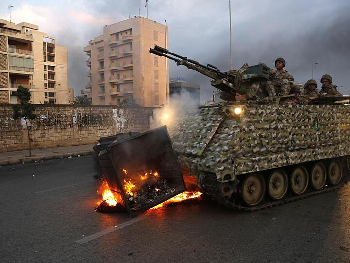 Ein gepanzertes Fahrzeug der Armee beseitigt eine brennende Mülltonne. Seit Tagen kommt es im Libanon zu Massenprotesten gegen die Regierung.