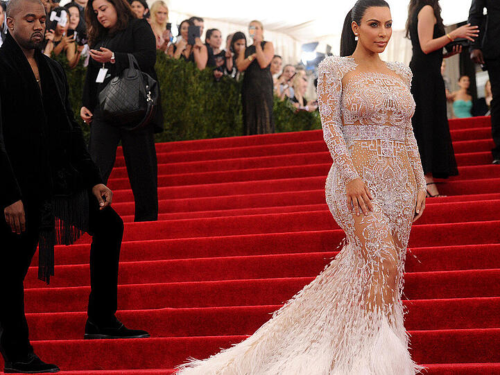 Auch Kim Kardashian gewährte einige Einblicke auf der Met Gala. Sie erschien in einer weißen, figurbetonten Kreation mit Nude-Effekt von Roberto Cavalli. Silberne Kristalle und eine lange, weiße Feder-Schleppe machten das Kleid zum Hingucker.