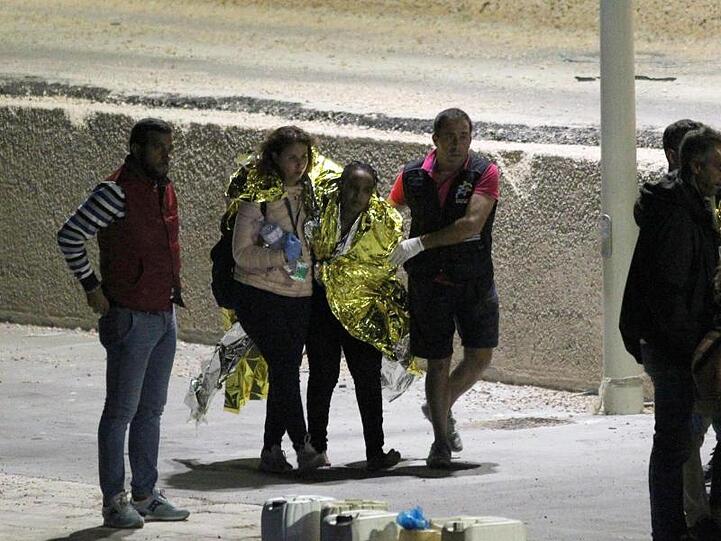 Migranten werden am Hafen von Lampedusa von Helfern begleitet. Mindestens 13 Menschen waren Anfang Oktober bei einem Bootsunglück vor der italienischen Insel ums Leben gekommen.