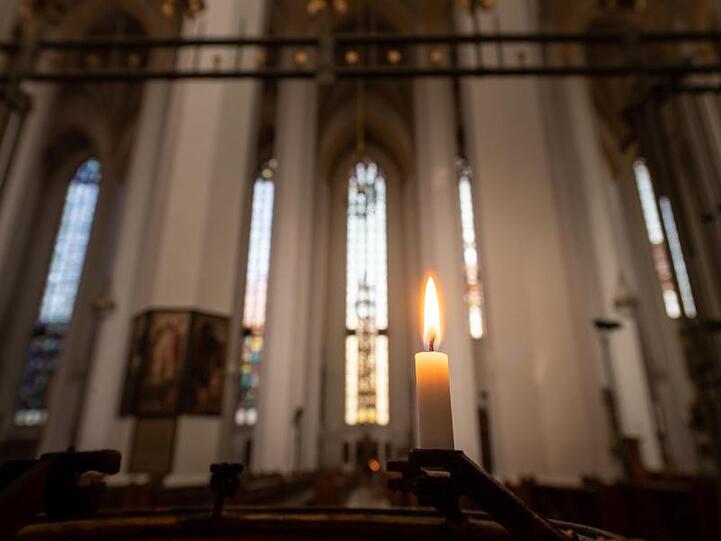 Ein Kerze brennt in der Frauenkirche. Foto: Peter Kneffel/dpa/Archivbild