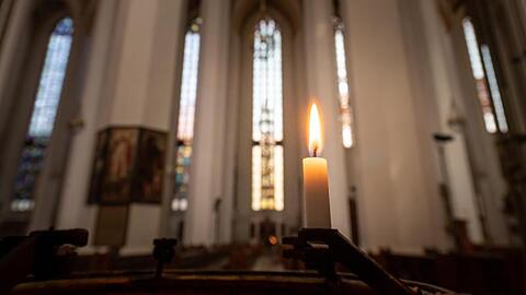 Ein Kerze brennt in der Frauenkirche. Foto: Peter Kneffel/dpa/Archivbild