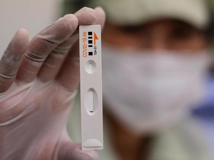 Ein Mitarbeiter von Boditech Med hält ein Teströhrchen für einen Covid-19-Antikörpertest in der Hand.