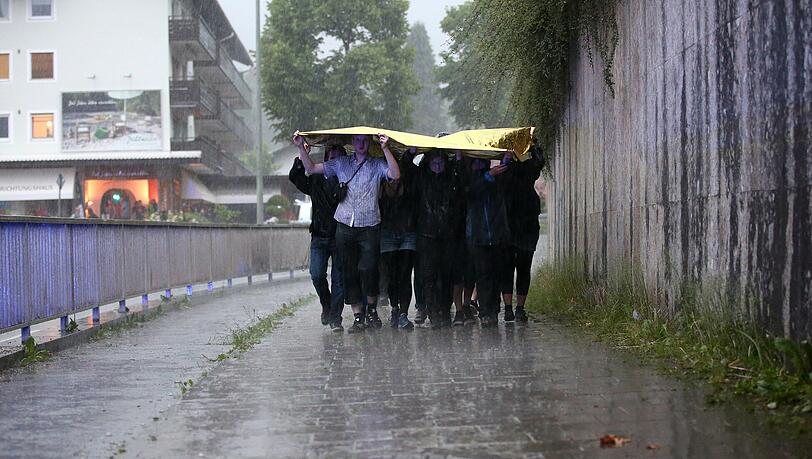 Mit einer Folie versuchen sich Menschen in Garmisch vor dem Regen zu schützen. Mit einer Folie versuchen sich Menschen in Garmisch vor dem Regen zu schützen.