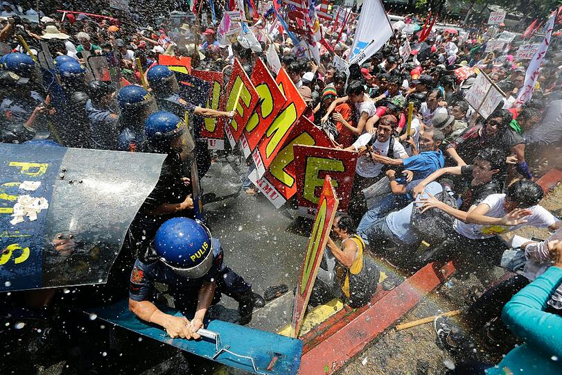 Demonstranten werden von Polizeikräften mit Wasserwerfen auseinander getrieben während einer Protestkundgebung gegen den Besuch von US-Präsident Barack Obama in Manila.