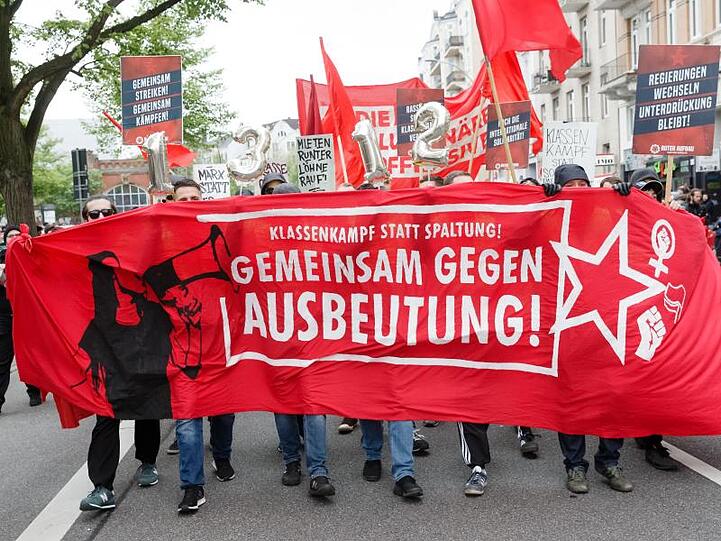 Demonstranten tragen ein Transparent mit der Aufschrift "Klassenkampf statt Spaltung. Gemeinsam gegen Ausbeutung" durch Hamburg.