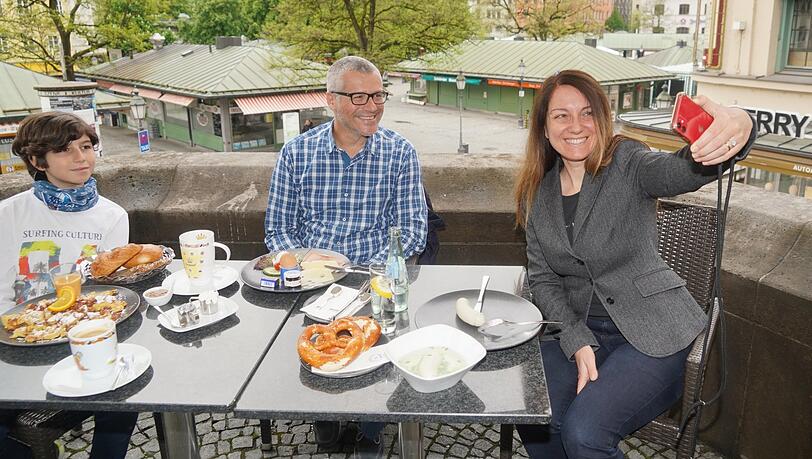 Auch Mütter feiern am Vatertag mit, betont Silvia (rechts), die mit ihrer Famile am Donnerstagmorgen am Rischart über dem Viktualienmarkt sitzt. "Wunderbar, endlich wieder draußen sitzen zu können und mit der Familie zu frühstücken", sagt sie. "Wir gönnen uns ein klassisches Frühstück mit Weißwurst und Apfelstrudel und außerdem Kaiserschmarrn." Dazu gibt es ein Selfie - ist ja schließlich ein besonderer Moment, endlich wieder ins Café gehen zu können. Auch Mütter feiern am Vatertag mit, betont Silvia (rechts), die mit ihrer Famile am Donnerstagmorgen am Rischart über dem Viktualienmarkt sitzt. "Wunderbar, endlich wieder draußen sitzen zu können und mit der Familie zu frühstücken", sagt sie. "Wir gönnen uns ein klassisches Frühstück mit Weißwurst und Apfelstrudel und außerdem Kaiserschmarrn." Dazu gibt es ein Selfie - ist ja schließlich ein besonderer Moment, endlich wieder ins Café gehen zu können.